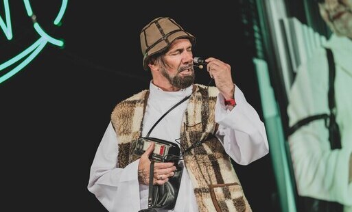 artysta przebrany za pastuszka śpiewa do mikrofonu